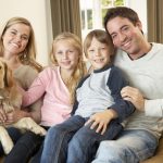 Ridgefield home - Happy young family sitting on sofa holding a dog