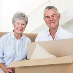 Cheerful senior couple moving into new home smiling at camera